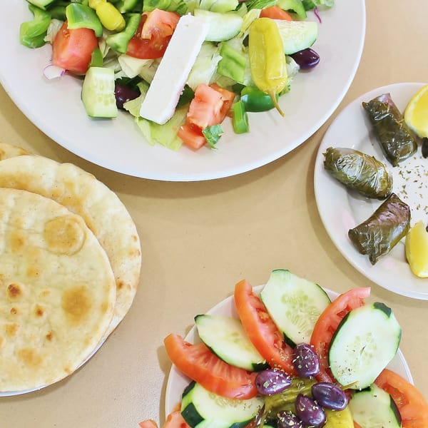 Plates of Greek salad with feta, dolmades, and pita bread from Hub's Restaurant.